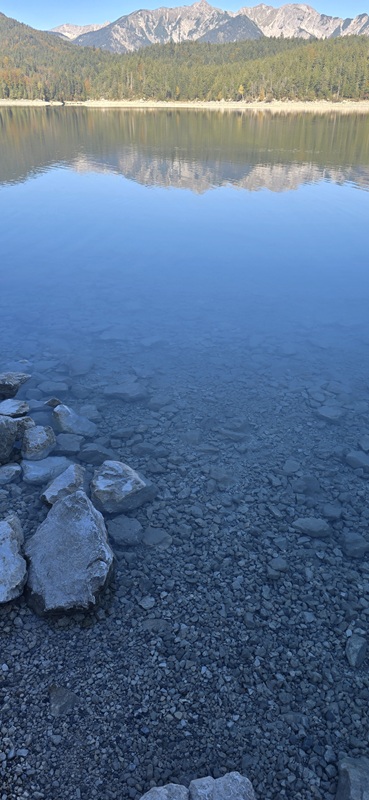 Uferbereich des Eibsees mit glasklarem Wasser und Blick auf die Zugspitzregion.
