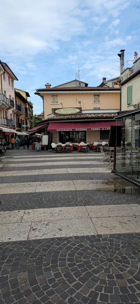 Gemütlicher Platz in der Altstadt von Lazise mit Cafés und historischen Gebäuden.