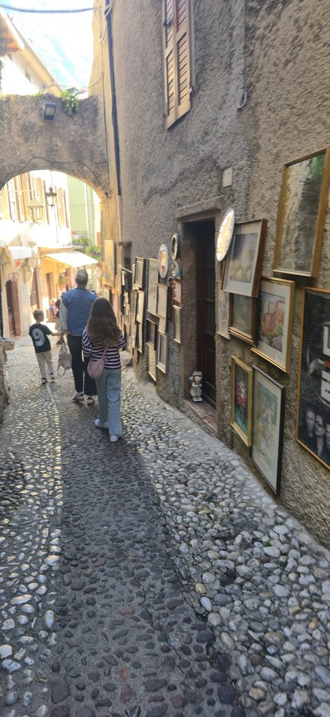 Schmale Altstadtgasse in Malcesine mit kleinen Geschäften und historischen Häusern.