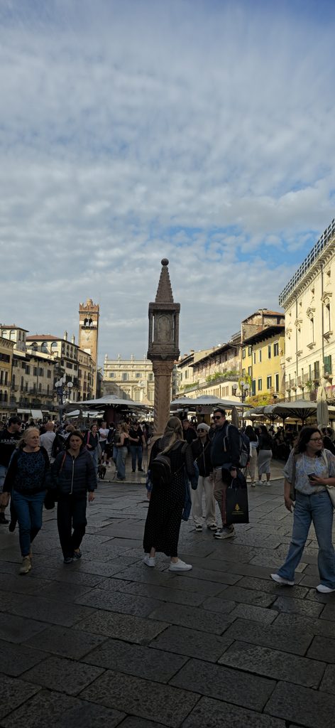 Piazza Erbe in Verona mit historischen Gebäuden und belebtem Marktplatz.