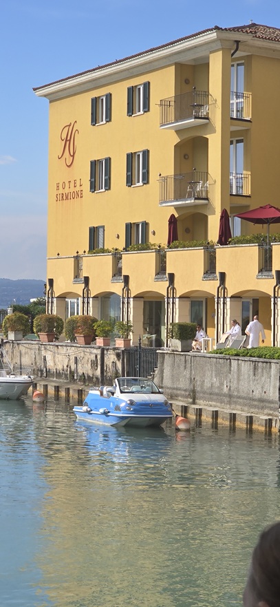 Hafenbereich von Sirmione mit historischen Gebäuden und Booten am Gardasee.