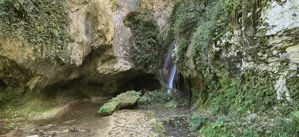 Kleiner Wasserfall im Naturpark Cascate di Molina umgeben von Felsen und üppiger Vegetation.